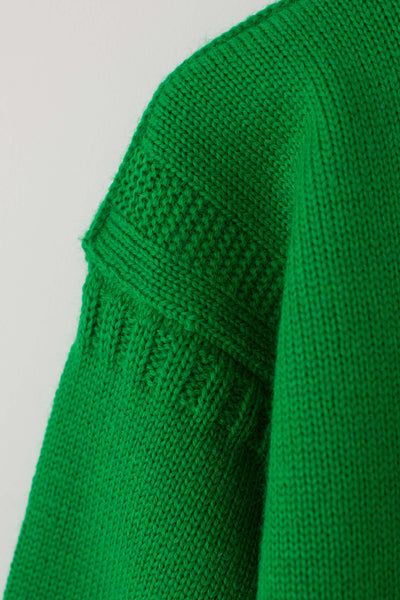 Model lying down with arms raised wearing a kelly green cropped guernsey