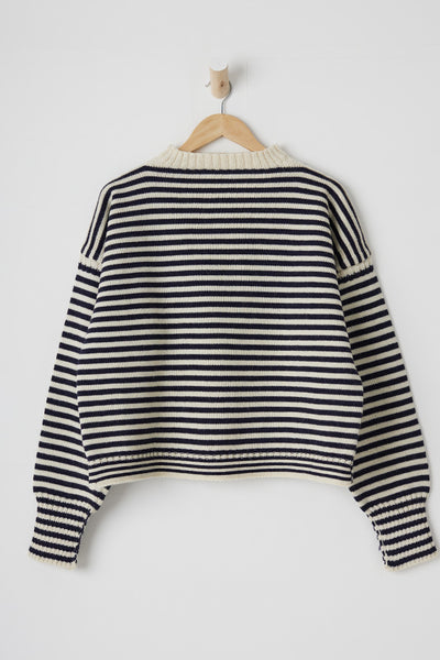 Model wearing an aran and navy striped cropped guernsey with a sunburst in the background