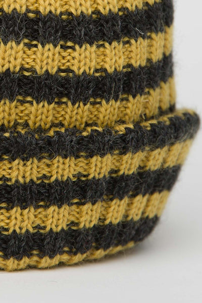 close up of a a charcoal grey & mustard yellow striped beanie