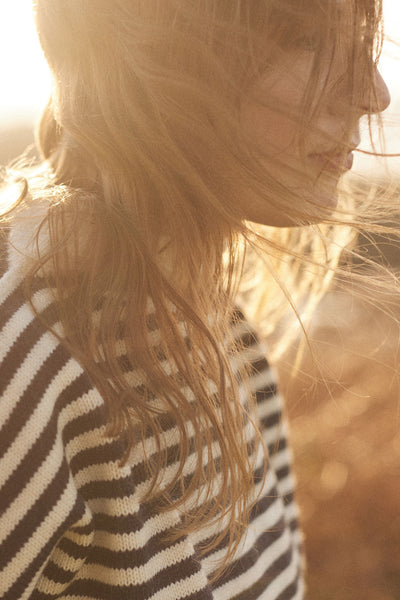Model wearing an aran and navy striped cropped guernsey with a sunburst in the background