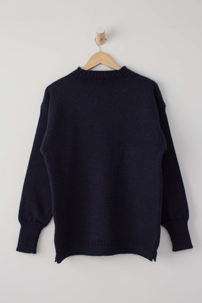 Traditional navy guernsey jumper hung on a wooden hanger