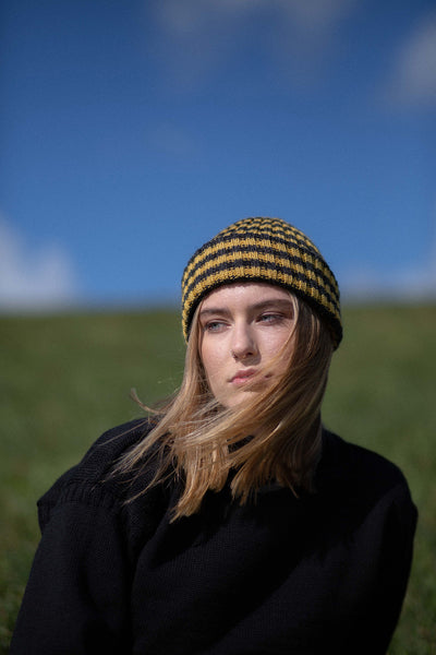 close up of a a charcoal grey & mustard yellow striped beanie