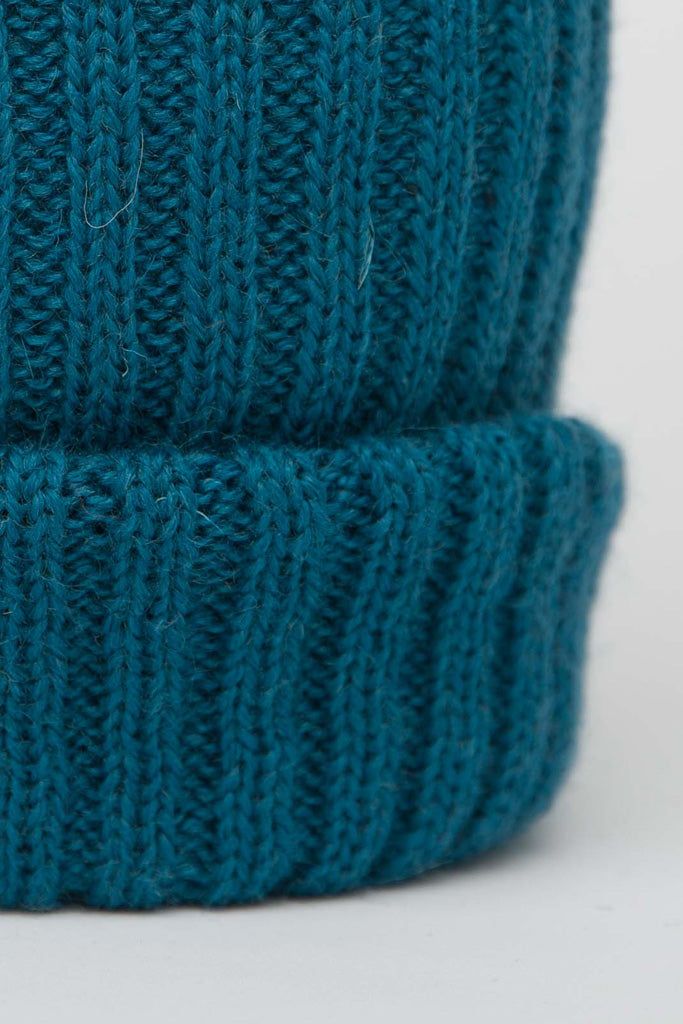 Close up of a beanie hat in a rich teal blue.